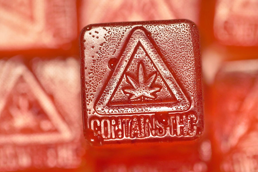 A close-up of a red cannabis gummy with a THC warning.