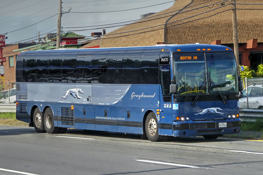 A Greyhound bus traveling along a busy roadway en route to Boston, showcasing the company’s role as a major intercity connection. For Long Island travelers, Greyhound provides an affordable and convenient way to reach destinations across the Northeast, including New York City, Philadelphia, and Boston, without the need for a car.