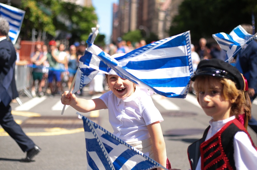 Young festivalgoers wave Greek flags with joy and pride, capturing the spirit of community and tradition that defines the Island Park Greek Festival. Expect cultural pride, colorful outfits, and plenty of family-friendly fun throughout the weekend celebration.