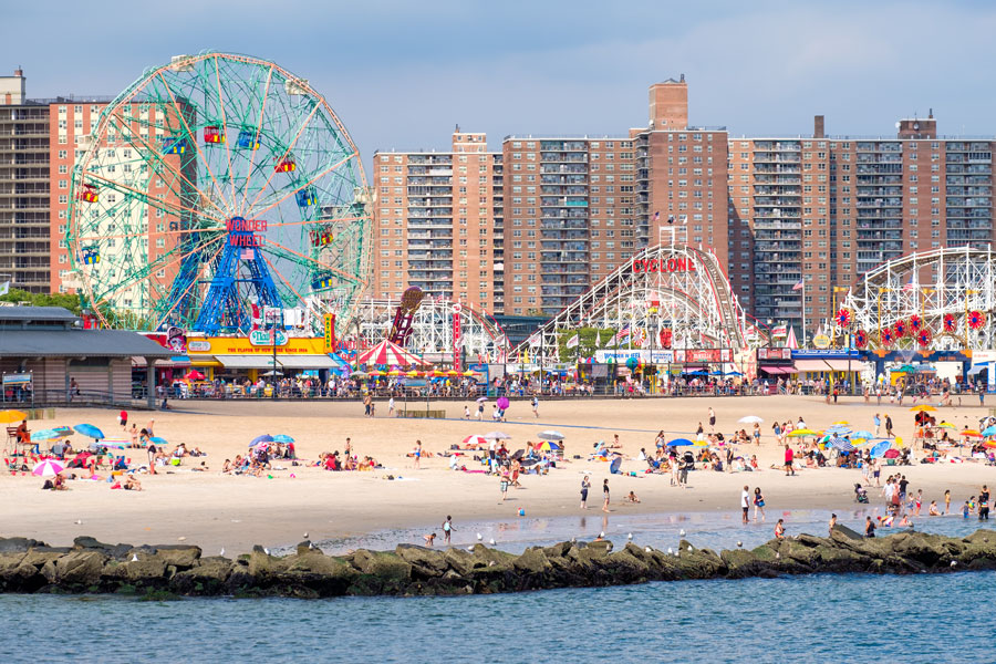 Beachgoers pack the sand at Coney Island while the historic Wonder Wheel and Cyclone roller coaster rise behind the boardwalk in Brooklyn, New York. Photo taken August 18, 2016.