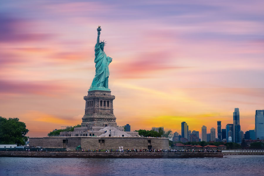 Located on Liberty Island, the Statue of Liberty has long symbolized freedom, democracy, and hope for millions who arrived in America through nearby Ellis Island. In the background, the Manhattan skyline rises with modern skyscrapers, bridging the historic symbol of liberty with the contemporary energy of New York City. The reflection of the colorful sky across the water adds a serene yet powerful atmosphere to one of the world’s most iconic landmarks.