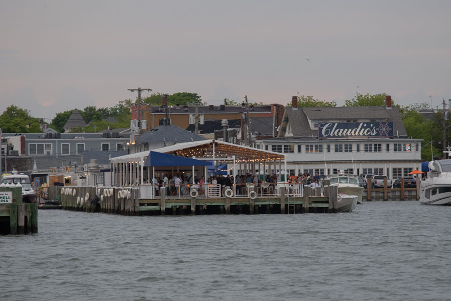 View of Greenport Village from the water on May 27, 2019, showing Mitchell Marina and the iconic Claudio’s restaurant on Long Island’s North Fork. The lively harbor scene captures the village’s maritime heritage and its reputation as a popular destination for dining, boating, and waterfront leisure.