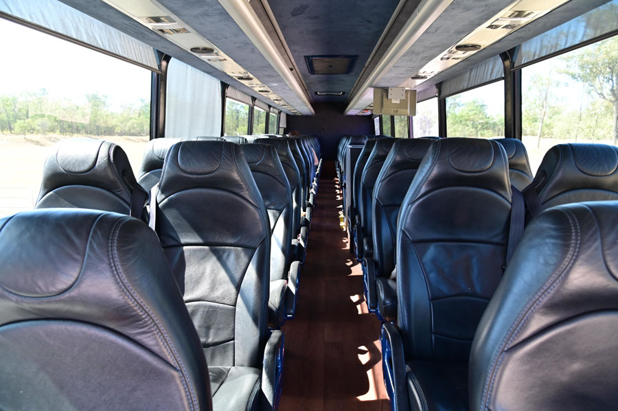 The interior of a Hampton Jitney motor coach features rows of comfortable, reclining leather seats with wide windows, offering passengers a relaxed and upscale travel experience between New York City and the Hamptons.