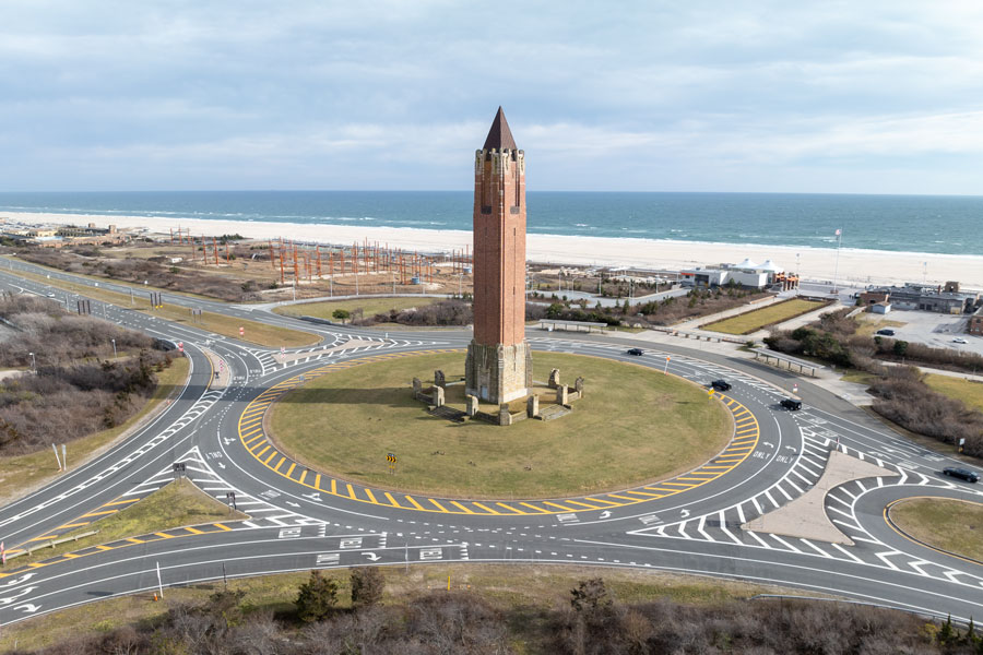 The iconic Jones Beach Water Tower, often called the pencil, stands tall at the heart of Jones Beach State Park on Long Island, New York. Photographed on a bright sunny day, the red-brick Art Deco tower is a recognizable landmark for visitors traveling to the Atlantic Ocean shoreline.