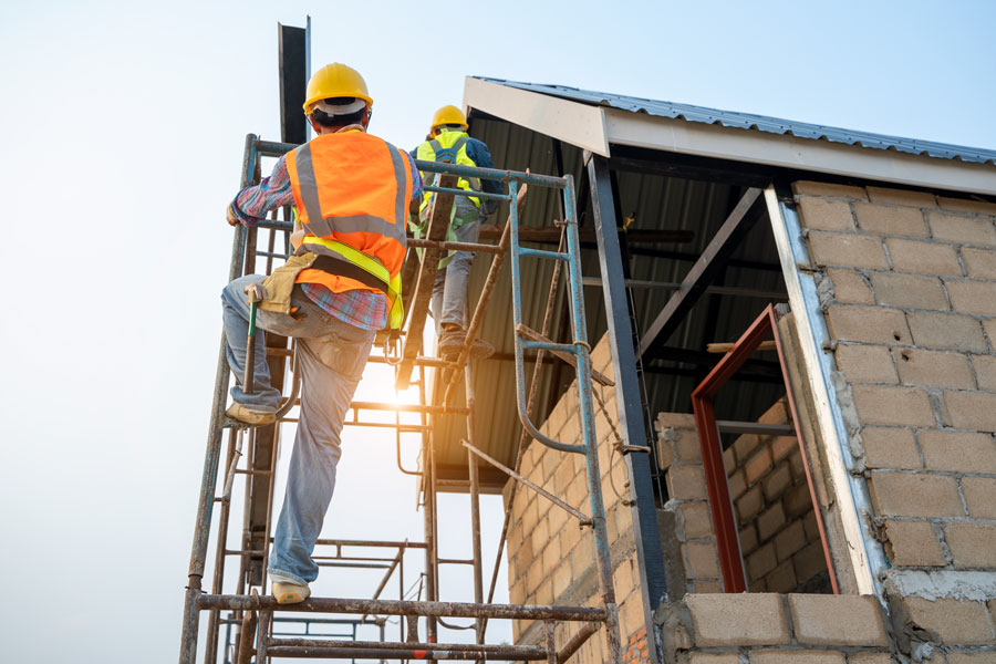 Construction workers climb scaffolding while working on a building project. A new bill in the New York State Assembly would remove the century-old Scaffold Law’s “absolute liability” standard for projects in Nassau and Suffolk counties. Supporters say the change could help reduce costs and deter fraudulent claims, while opponents warn it may weaken safety protections for workers.