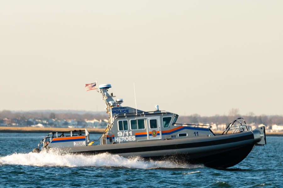 This image shows a Nassau County Police Marine Patrol boat actively navigating the waterways of south Nassau County, Long Island, New York on February 21, 2019. The boat is notably labeled "9/11 Heroes," indicating a tribute to first responders or victims of the September 11 attacks, and is equipped with emergency response features suitable for marine law enforcement activities in the region. 