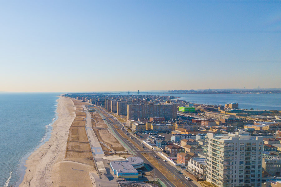 This sweeping aerial shot highlights Rockaway Beach, a popular seaside destination located on the Rockaway Peninsula in Queens. Known as the city’s go-to surf beach, it offers miles of sandy shoreline, a lively boardwalk, and designated surf areas that attract both locals and visitors during the summer months. Rockaway Beach is unique as the only beach in New York City with consistent surf breaks, making it a hub for the city’s surf culture. Beyond the waves, the neighborhood features beachfront concessions, playgrounds, biking paths, and easy subway access, creating a true urban escape by the sea. The expansive coastline shown here illustrates why Rockaway Beach is not only a recreational hotspot but also a beloved part of New York’s coastal identity.