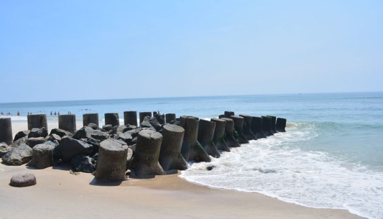 Remnants of an old fishing dock made of concrete and rocks along the beach at Ocean Beach, Fire Island, New York, with calm Atlantic Ocean waves under a clear blue sky.