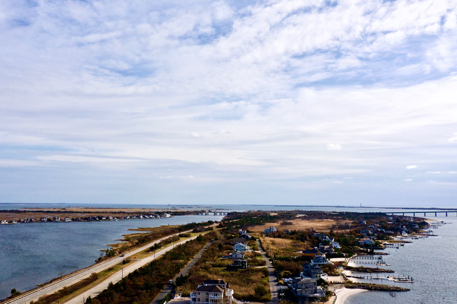 Aerial photo of Oak Beach, New York, showing waterfront homes, Ocean Parkway, and the Great South Bay under a partly cloudy sky on a calm morning.