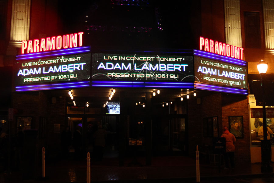 Exterior night view of The Paramount theater in Huntington, New York, with its bright marquee advertising an Adam Lambert concert.