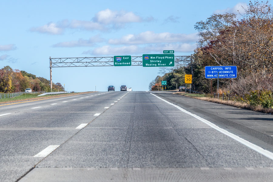 Highway view at Exit 68 on the Long Island Expressway (I-495) showing signs for William Floyd Parkway toward Shirley and Wading River. The roadway stretches east toward Riverhead, providing access to Montauk and the East End. 