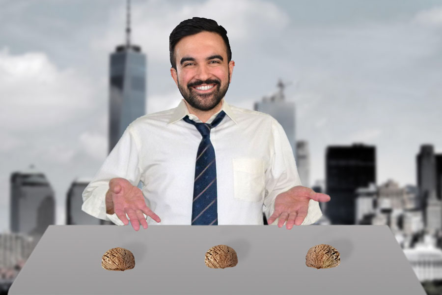 Zohran Mamdani, stands smiling behind a table with three walnut shells, arranged like a traditional shell game, against the New York City skyline.