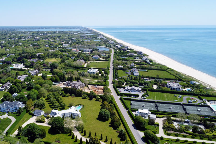 Aerial view of Hampton Bays, New York, showing oceanfront homes, beaches, and residential neighborhoods along the South Fork of Long Island.