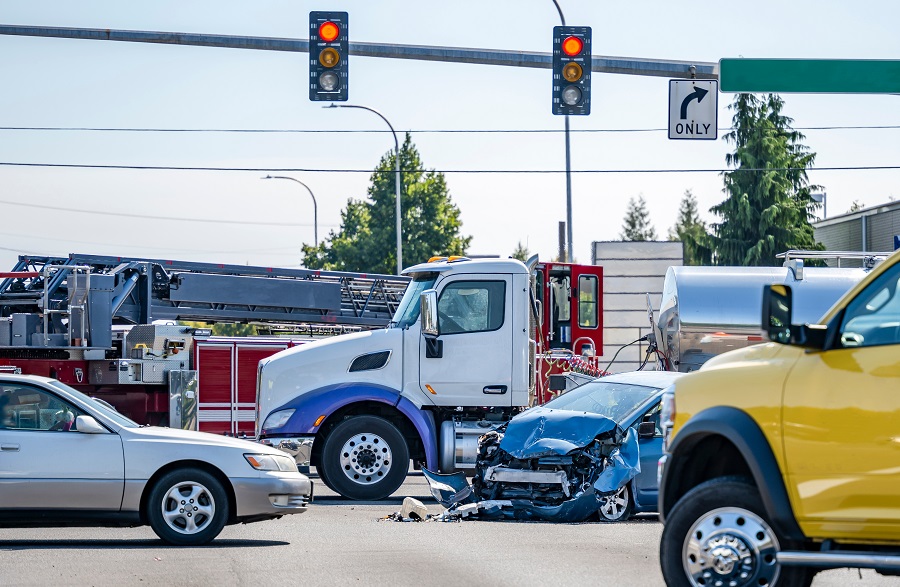 Severe multi-vehicle accident at an intersection involving a passenger car and a truck, with emergency vehicles on scene.