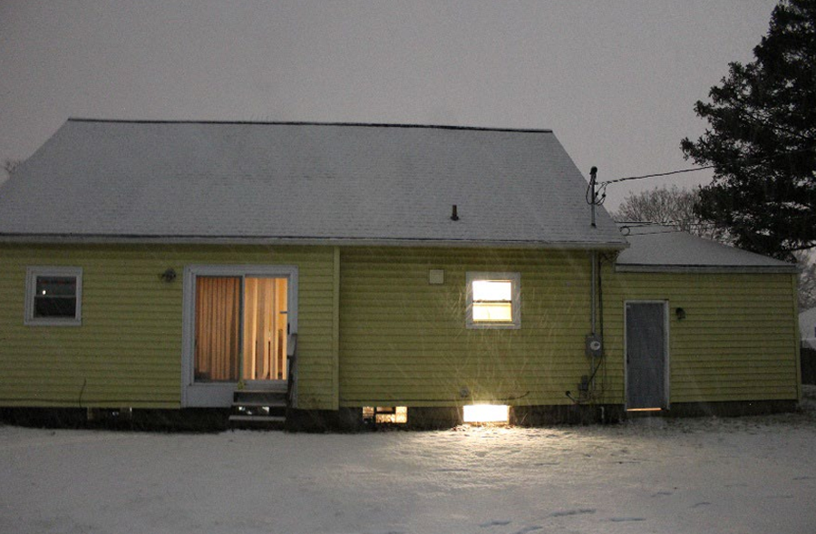 Exterior night view of the house labeled Group Premises 1 in the indictment, where law enforcement reported finding nine adult men living with little furniture and multiple mattresses on the floor.