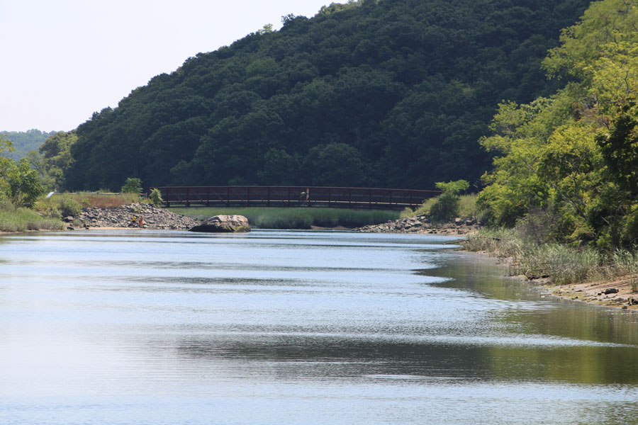 Footbridge spanning the creek at Sunken Meadow State Park in Kings Park, New York, surrounded by trees and natural waterfront scenery.