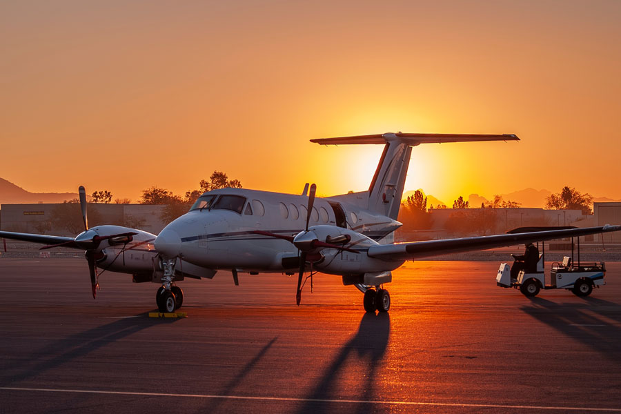 Beechcraft King Air turboprop aircraft parked on an airport ramp at sunset.