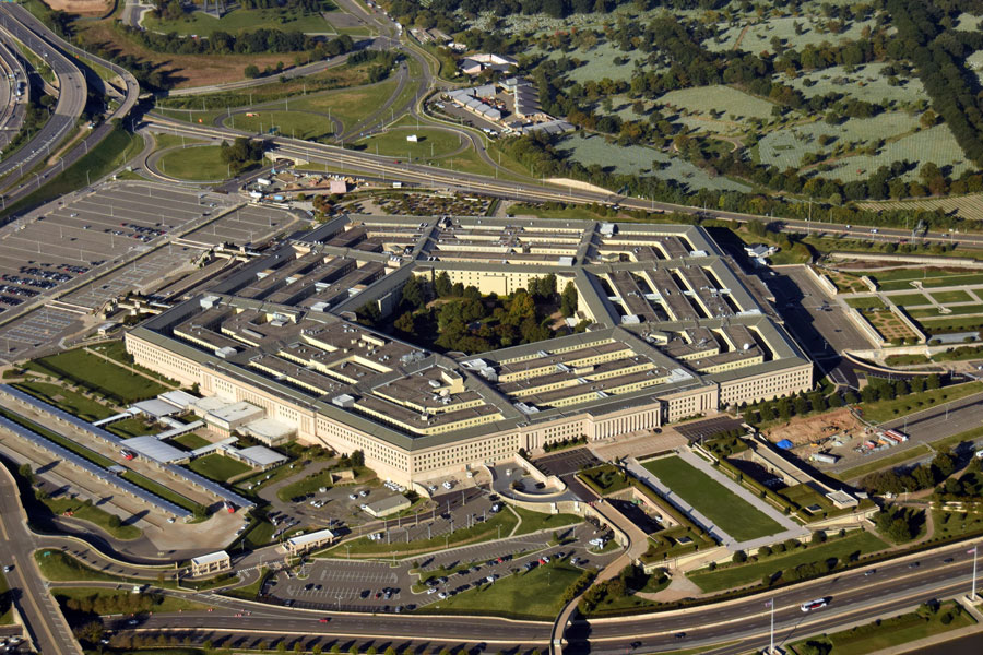 Aerial photograph of the Pentagon building in Arlington, Virginia, showing its five-sided structure, surrounding roads, and parking areas.