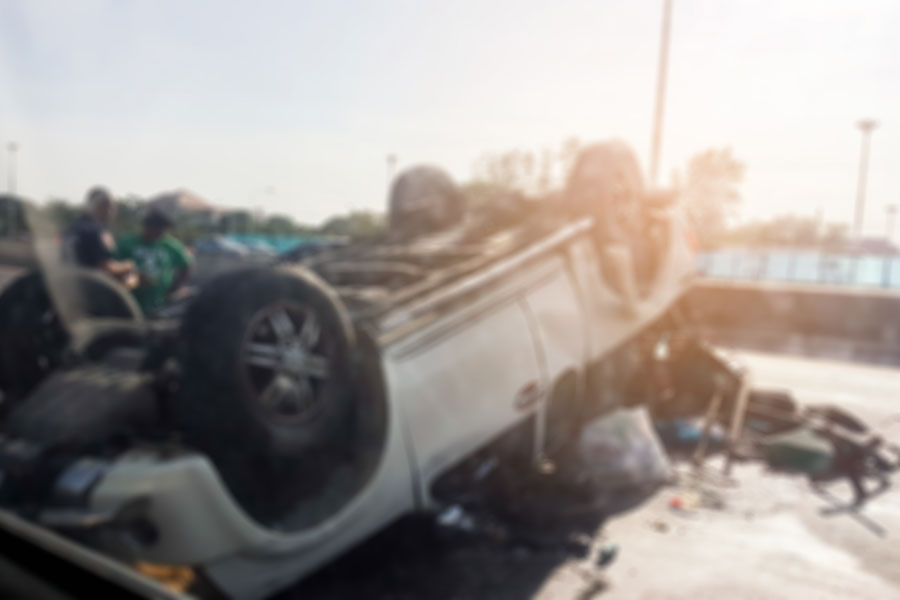 Overturned vehicle at crash scene with responders nearby, representing dangers of drugged driving and impaired motorists on New York roads.