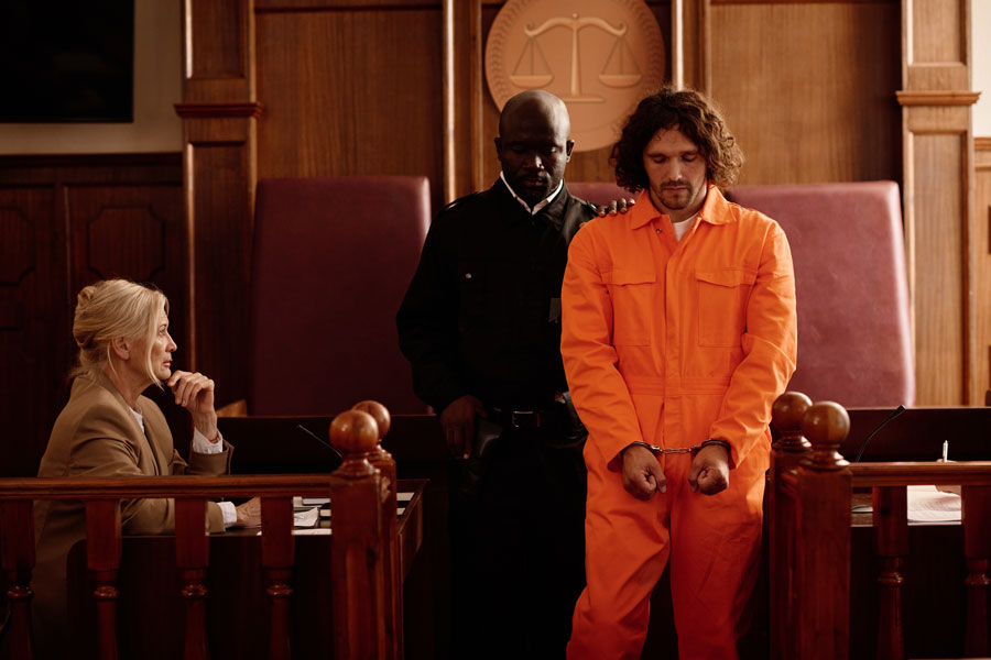 Defendant in handcuffs standing before a judge during criminal court sentencing proceedings.