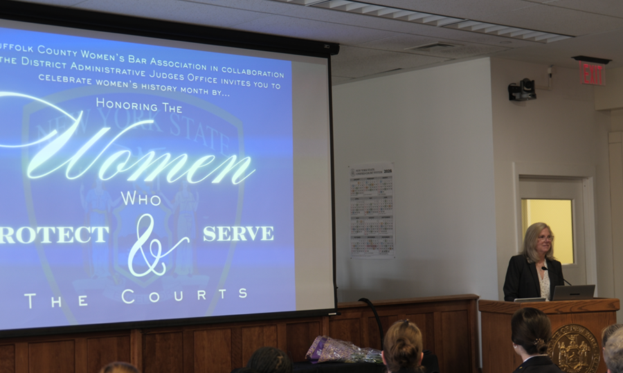 A presentation highlights the theme “Women Who Protect & Serve the Courts” during the Suffolk County Courts’ Women’s History Month ceremony.