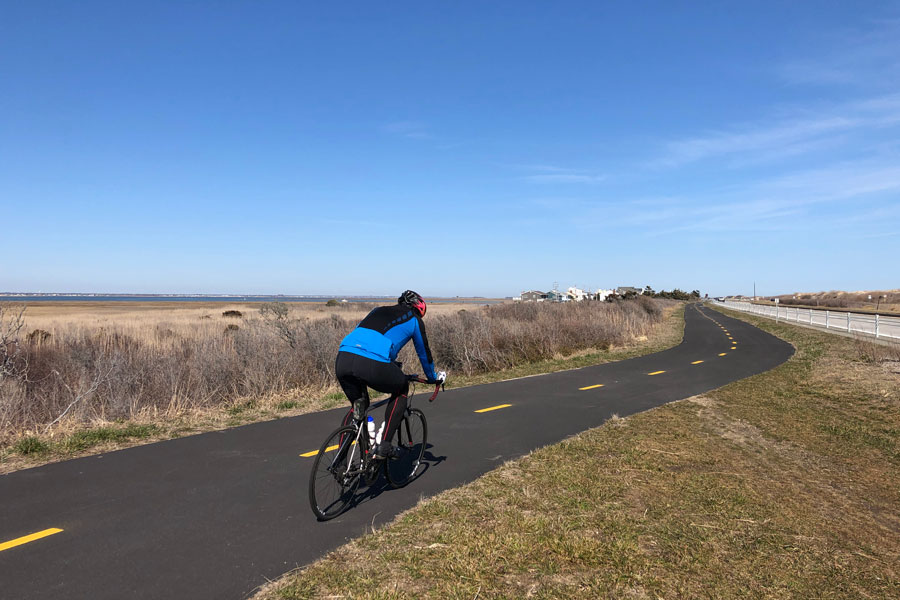 A cyclist rides along the Ocean Parkway Coastal Greenway on Jones Beach Island, one of Long Island’s most popular paved recreation trails. The scenic path follows the South Shore barrier island system and provides access to beaches, marshlands, bay views, and coastal parks near Jones Beach and surrounding waterfront destinations. File photo: licensed.