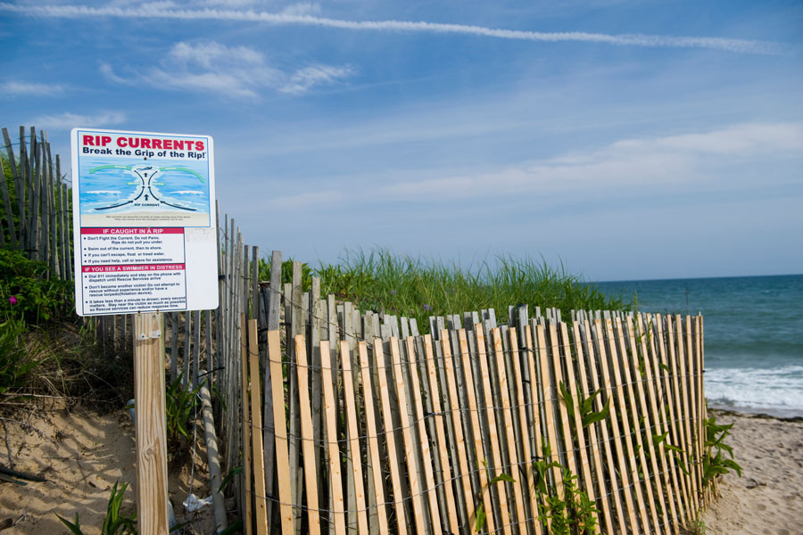 A rip current warning sign stands near the dunes at Ditch Plains Beach in Montauk, one of Long Island’s most recognized surf destinations. Strong Atlantic Ocean conditions and changing wave patterns make ocean safety an important part of the beach experience along the South Fork shoreline.