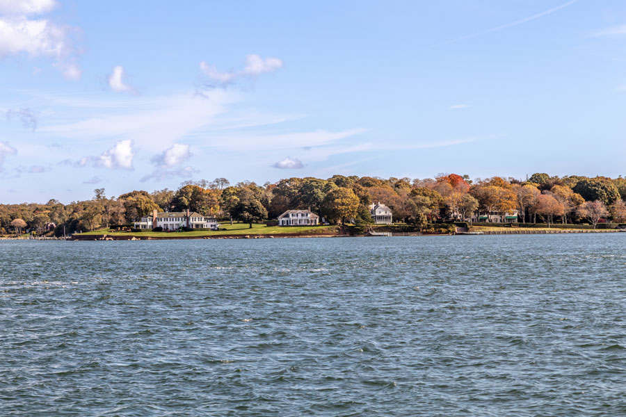 Waterfront homes line the shoreline near Shelter Island Heights as viewed from the surrounding East End waterways near Greenport. The hamlet is known for its historic character, marina culture, ferry connections, and quieter coastal atmosphere between Long Island’s North Fork and South Fork.