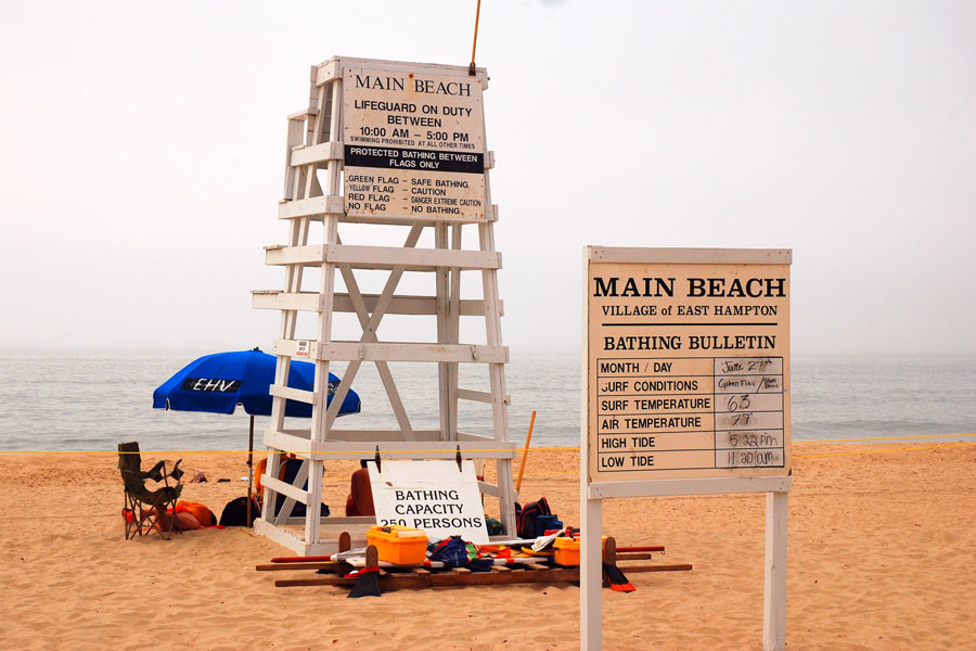 A lifeguard tower and beach conditions board stand along the sand at Main Beach in East Hampton, one of the Hamptons’ most recognized Atlantic Ocean destinations. During the summer season, visitors gather here for swimming, sunbathing, and coastal recreation along the South Fork shoreline.