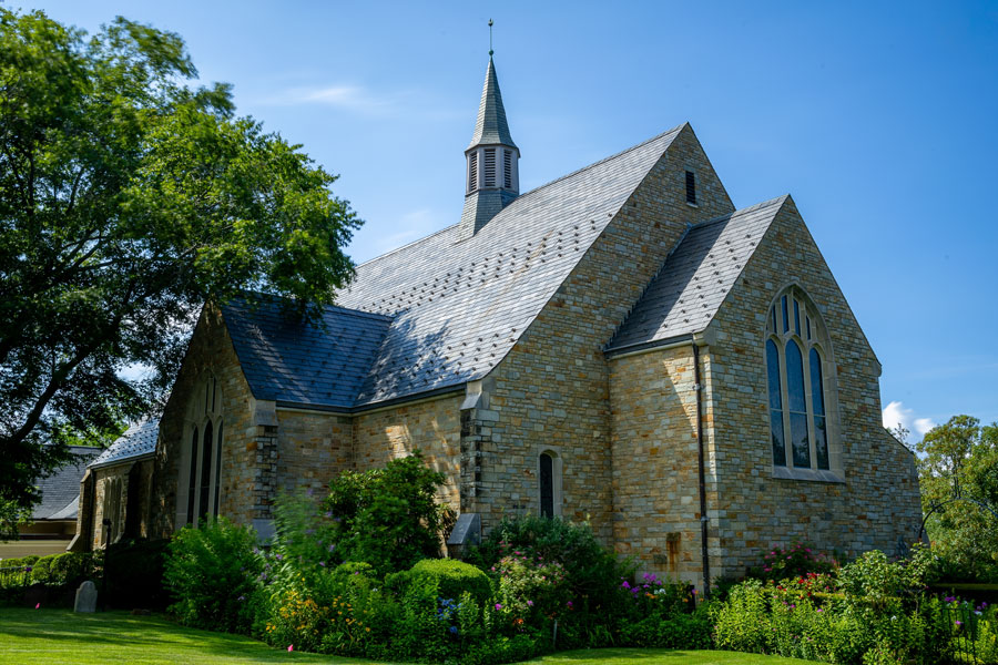 Christ Church Oyster Bay photographed on July 10, 2025, in Oyster Bay, New York. The historic stone church stands beneath a bright summer sky as blurred leaves and soft trailing clouds create a tranquil North Shore scene. File photo: licensed.