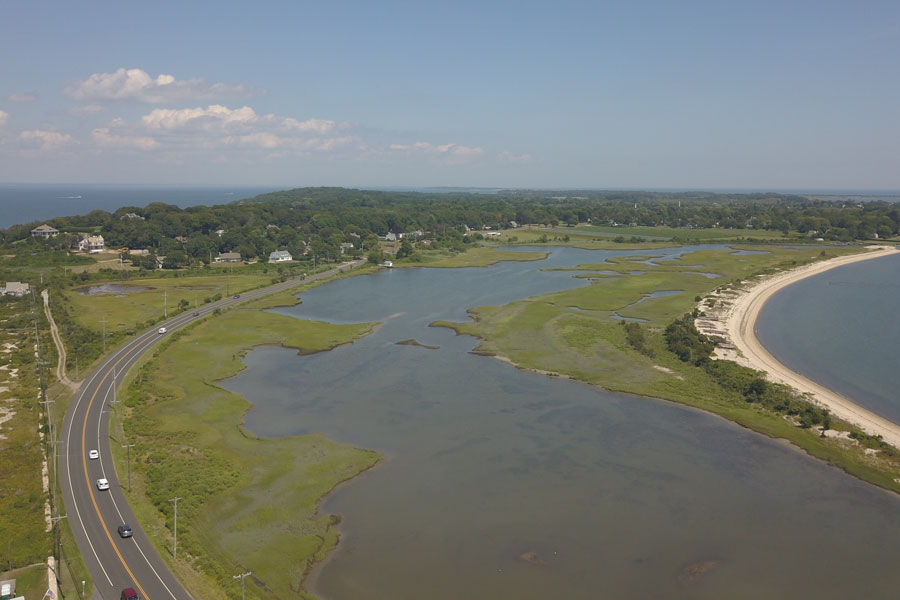 Aerial view of the coastal wetlands and shoreline near Orient on Long Island’s North Fork, where quiet roads wind past salt marshes, sandy beaches, and protected waterfront landscapes overlooking Gardiners Bay and the eastern end of Suffolk County, New York.