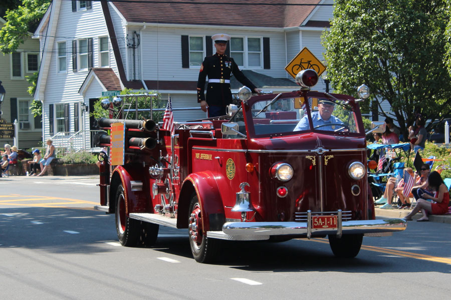 A uniformed serviceman rides atop a vintage fire truck during a Fourth of July parade in Port Jefferson Station, New York, on July 4, 2019, as spectators line the street to celebrate Independence Day.