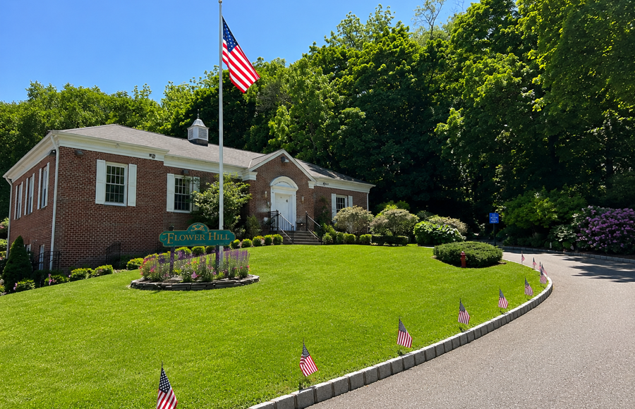 Flower Hill Village Hall in the Incorporated Village of Flower Hill, New York, decorated with American flags ahead of Memorial Day celebrations. Located at 1 Bonnie Heights Road, the building serves as the seat of village government on Long Island’s North Shore.
