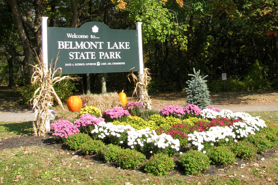The entrance sign for Belmont Lake State Park welcomes visitors to one of western Suffolk County’s most popular outdoor recreation destinations. Surrounded by seasonal flowers, pumpkins, and landscaped gardens, the display reflects the park’s family-friendly atmosphere and year-round appeal. Centered around scenic Belmont Lake, the park attracts visitors for fishing, boating, picnicking, walking trails, wildlife viewing, and seasonal events throughout the year.