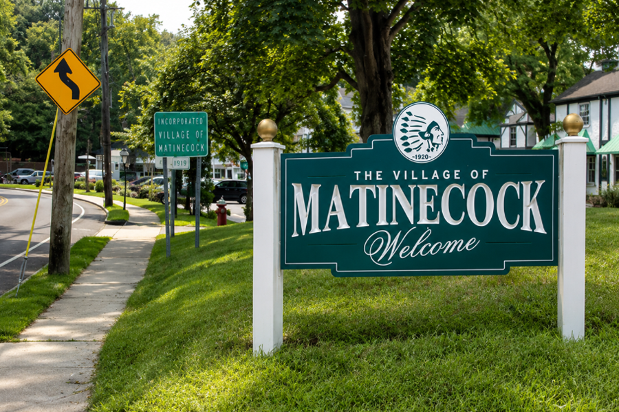 The welcoming entrance sign for the Village of Matinecock stands along a tree-lined roadway on Long Island’s North Shore. Surrounded by manicured lawns, mature shade trees, and historic village character, the sign marks the entrance to one of Nassau County’s most exclusive and picturesque communities. The scene reflects the quiet residential atmosphere and timeless charm that define Matinecock.