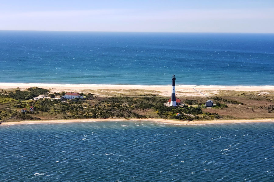An aerial view of the Fire Island Lighthouse and surrounding barrier island landscape. Located near the western end of Fire Island, the historic lighthouse overlooks both the Atlantic Ocean and Great South Bay and remains one of Long Island's most recognizable landmarks.