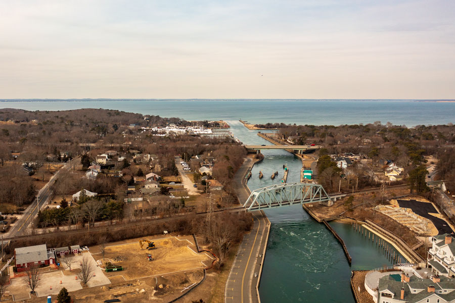 An aerial view of the Shinnecock Canal in Hampton Bays, showing the waterway that links the Peconic Bay system with Shinnecock Bay and the Atlantic Ocean beyond. Completed in 1892, the canal serves as one of Long Island’s most important maritime corridors, supporting recreational boating, commercial fishing, and marine navigation throughout the East End. The canal also marks the traditional dividing line between the North Fork and South Fork, making it a significant geographic landmark on Long Island.