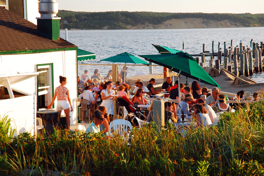 Diners enjoy waterfront dining along Long Island’s scenic coastline as the sun begins to set, creating a relaxed atmosphere overlooking the harbor. From fresh local seafood to spectacular water views, the island’s waterfront restaurants are among the best places to experience Long Island’s coastal charm and vibrant dining scene.