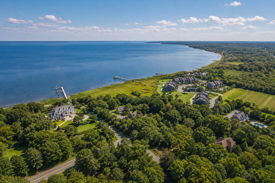 Aerial view of Baiting Hollow overlooking the Long Island Sound, where wooded landscapes, waterfront homes, open green space, and nearby vineyards showcase the community's rural coastal character. Situated along the western gateway to the North Fork, Baiting Hollow is known for its scenic shoreline, wineries, golf courses, and peaceful countryside setting.