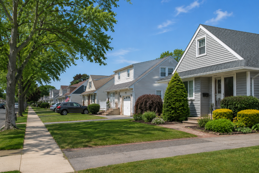 A quiet residential street in East Massapequa, New York, features well-maintained homes, mature shade trees, and neatly landscaped front lawns that reflect the community's welcoming suburban character. Located along Long Island's South Shore, East Massapequa is known for its established neighborhoods, convenient location, and family-friendly atmosphere.