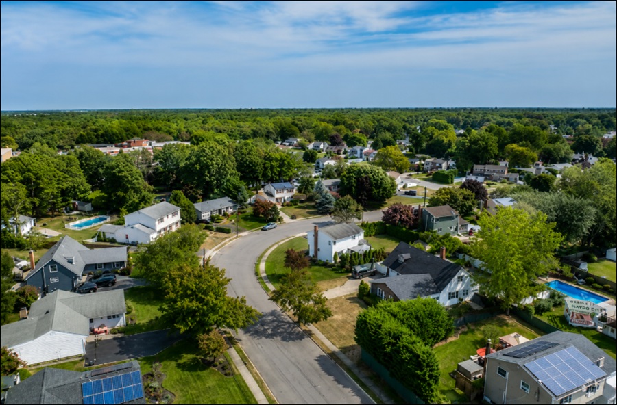 An aerial view of North Bayport, New York, overlooks a peaceful residential neighborhood with tree-lined streets, well-maintained single-family homes, and spacious yards. Mature landscaping, quiet suburban roads, and nearby wooded areas reflect the community's tranquil character and its convenient location near Bayport, Sayville, and the Great South Bay on Long Island.