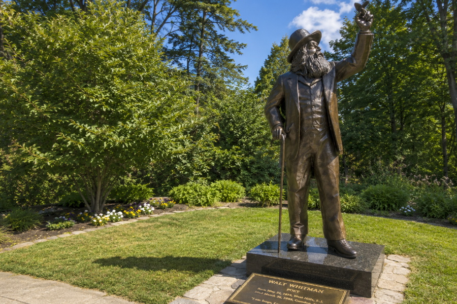 A statue of Walt Whitman stands on the grounds of the Walt Whitman Birthplace State Historic Site in West Hills, honoring one of America's most influential poets. Surrounded by landscaped gardens and mature trees, the memorial celebrates Whitman's enduring connection to Long Island and his lasting contributions to American literature.