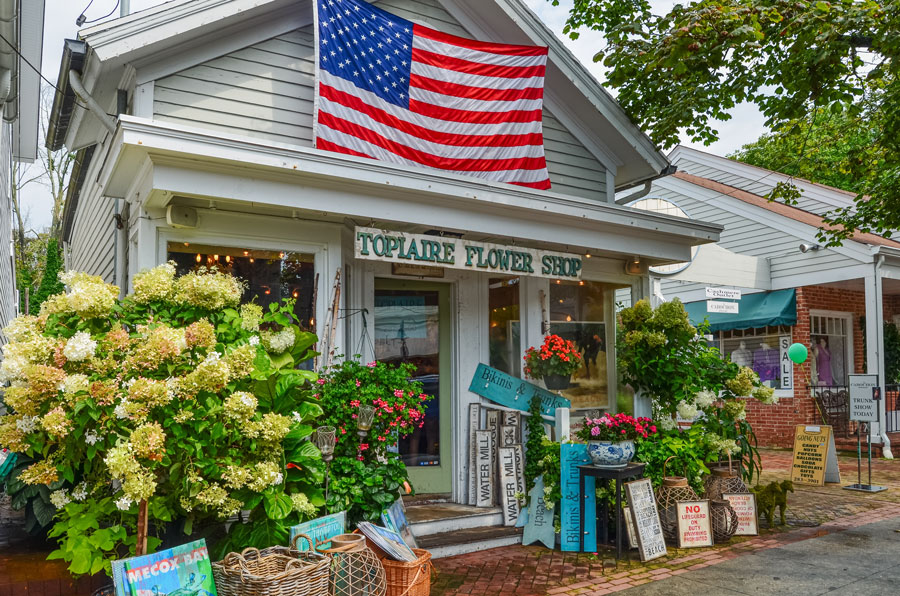 A charming flower shop lines one of Southampton's picturesque village streets, reflecting the small-town character and historic charm that have defined the Hamptons for generations. While the region is now known worldwide for its beaches, luxury homes, and seasonal visitors, many of its downtowns continue to preserve the welcoming atmosphere and local businesses that trace their roots to centuries of Long Island history. File photo: Conny Pokorny, licensed.