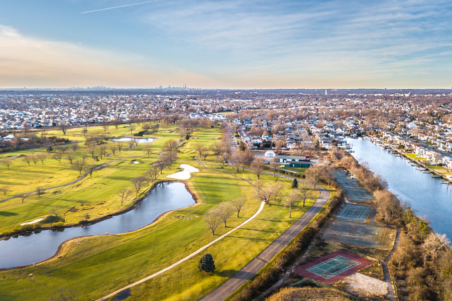 Aerial view of the Hewlett area showing a golf course, residential neighborhoods, and the tidal waterways that characterize Long Island's South Shore. Hewlett Bay Park is known for its spacious residential properties, mature landscaping, and proximity to these protected coastal waters.