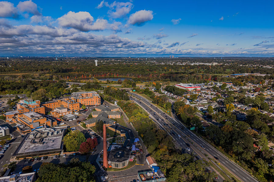 An aerial view of Mercy Hospital in Rockville Centre, with the hospital campus, surrounding neighborhoods, and nearby Southern State Parkway visible beneath blue autumn skies. Photographed on October 20, 2025.
