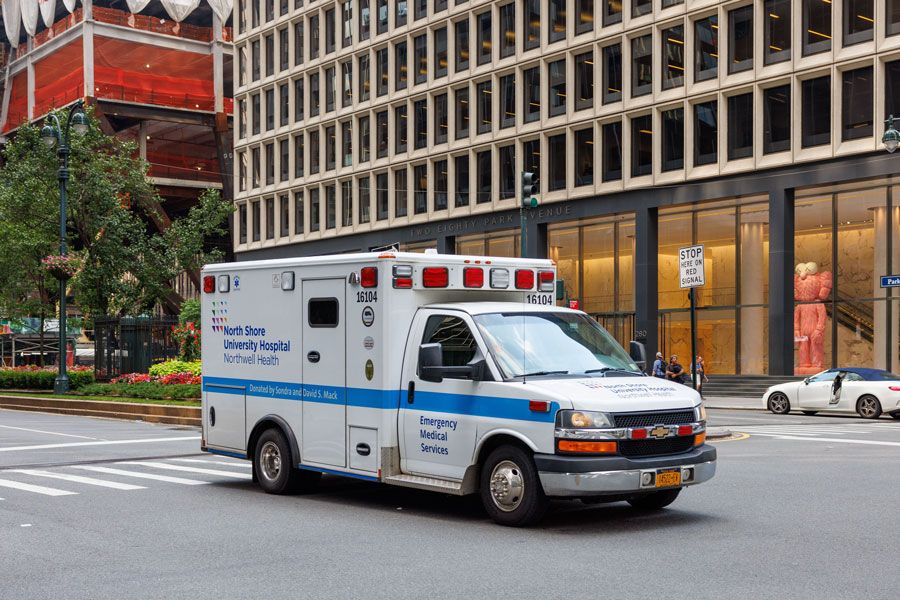 An ambulance from North Shore University Hospital, part of the Northwell Health system, responds through Midtown Manhattan while providing emergency medical services. The hospital's emergency department and Level I Trauma Center in Manhasset serve patients throughout Long Island, New York City, and the surrounding metropolitan region, transporting critically ill and injured patients for advanced specialized care.