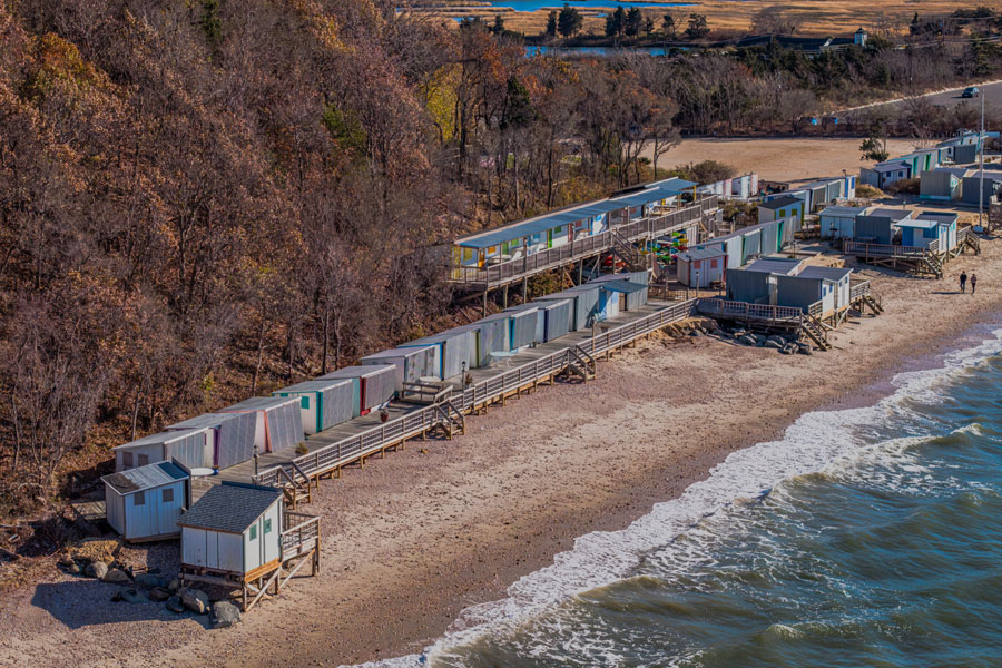 An aerial view of the Old Field Club’s private beach and cabanas along Smithtown Bay in East Setauket. The shoreline illustrates the bay’s mix of waterfront recreation, wooded coastal land, and residential surroundings on Long Island’s North Shore.