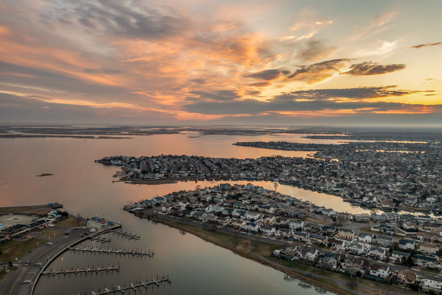 An aerial view of South Shore waterfront communities at sunset showcases the interconnected bays, canals, marinas, and residential neighborhoods that define much of Long Island's southern coastline. Stretching from Queens through Nassau and Suffolk counties, the South Shore is known for its boating culture, beaches, fishing, barrier islands, and scenic waterfront communities. File photo: ECL Media LLC, licensed.