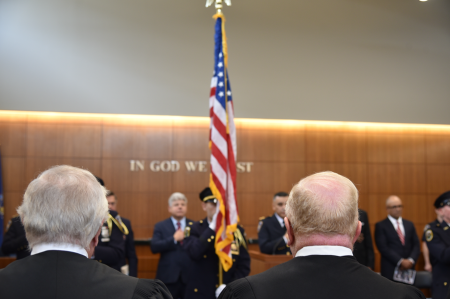 Chief of Public Safety for Suffolk Courts David Santiago leads the ceremony in the Pledge of Allegiance while Suffolk County judges look on.
