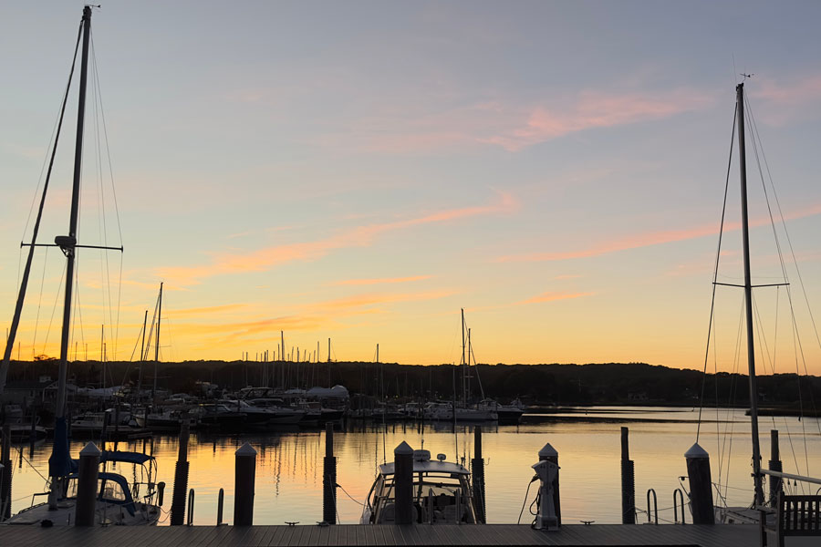 Boats rest quietly in a marina on Three Mile Harbor at sunset in East Hampton, New York. The protected harbor is one of the South Fork's most popular destinations for recreational boating, sailing, fishing, and waterfront dining.